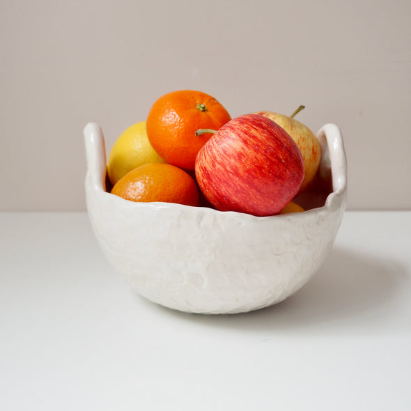 pink and white ceramic bowl with handles with fruit