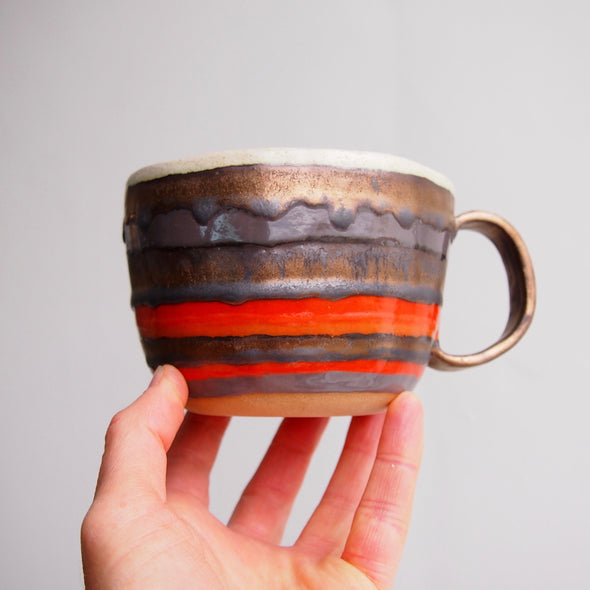 Handmade pottery mug with gold, orange and grey.