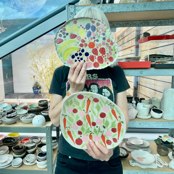 Handmade ceramic platter with fruits and vegetables & curvy top edge.