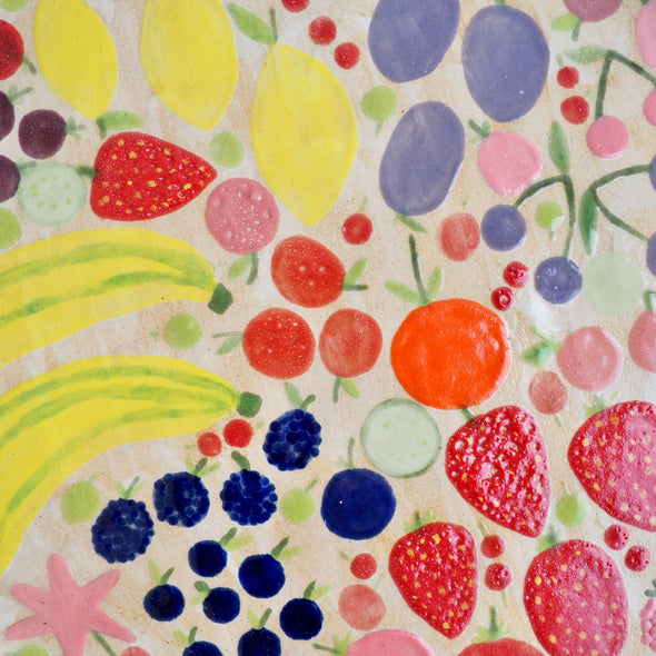 Handmade ceramic platter with fruits and vegetables & curvy top edge.