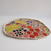 Handmade ceramic platter with fruits and vegetables & curvy top edge.