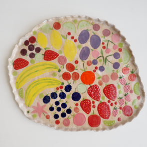 Handmade ceramic platter with fruits and vegetables & curvy top edge.