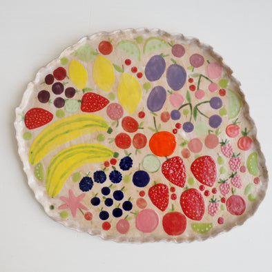 Handmade ceramic platter with fruits and vegetables & curvy top edge.