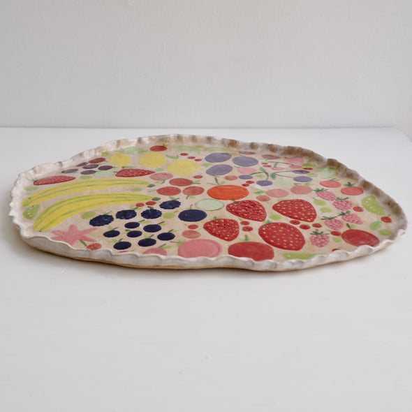 Handmade ceramic platter with fruits and vegetables & curvy top edge.