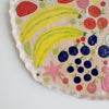 Handmade ceramic platter with fruits and vegetables & curvy top edge.