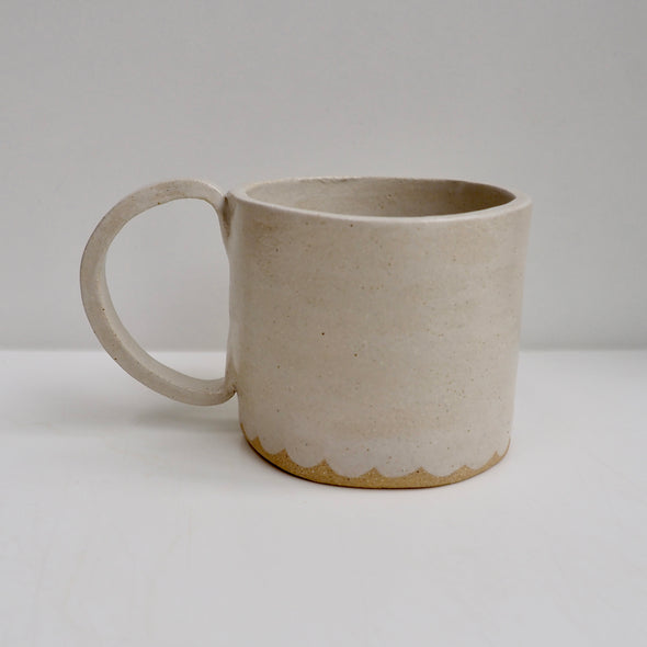 Cream ceramic mug with a scalloped lower edge