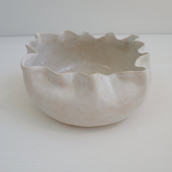 Handmade white speckled  ceramic serving bowl with curvy top edge.