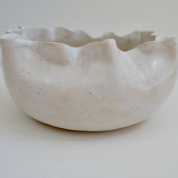 Handmade white speckled  ceramic serving bowl with curvy top edge.