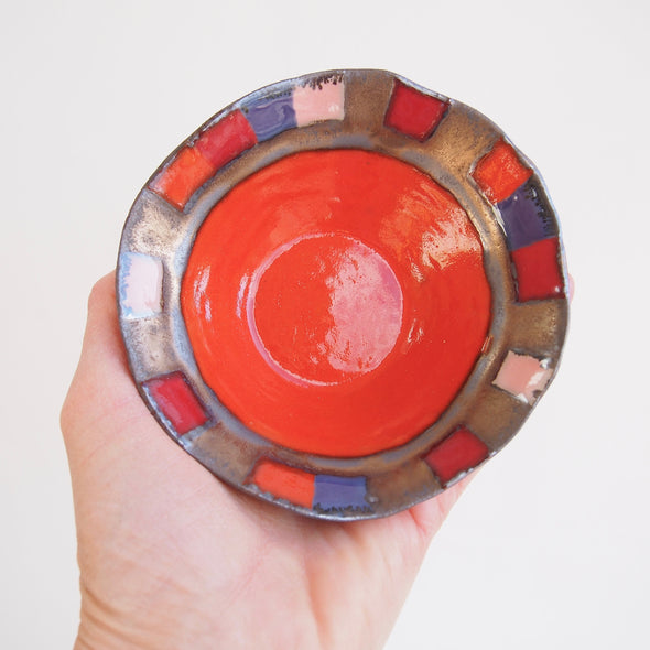 Orange ceramic ring dish with pink, red and purple squares and gold detail.